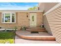 Inviting front porch featuring a decorative door, flowers, and a brick facade at 11530 Elm Ct, Thornton, CO 80233