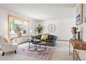Bright living room featuring a large bay window, neutral carpet, and a decorative rug at 11530 Elm Ct, Thornton, CO 80233