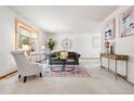 Bright living room featuring a large bay window, neutral carpet, and a decorative rug at 11530 Elm Ct, Thornton, CO 80233