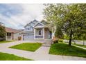 A beautiful two-story home with gray siding and a covered porch. Nicely landscaped front yard and two car garage at 15389 E 99Th Way, Commerce City, CO 80022