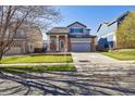Two story home with brick accents, gray siding, large front yard and attached two car garage at 16006 E 97Th Pl, Commerce City, CO 80022
