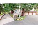 Exterior elevation with stone accents, mature trees and a three-car garage at 974 Spring Ranch Dr, Golden, CO 80401