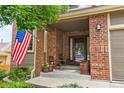 Inviting front porch with brick facade, seating, and an American flag displayed at 15962 W 70Th Dr, Arvada, CO 80007