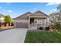 Inviting home featuring a two-car garage, well-maintained lawn and a charming front porch at 14431 Forest St, Thornton, CO 80602