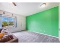 Open-concept living room with a large window, providing ample natural light, and a green accent wall at 18038 Becket Dr, Parker, CO 80134