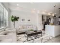 Bright living room featuring modern decor and light hardwood floors that opens up to the kitchen at 15345 W 69Th Dr, Arvada, CO 80007
