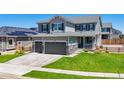 Two-story home featuring a three-car garage, stone accents, landscaped yard, and a well-maintained lawn at 9716 Uravan St, Commerce City, CO 80022