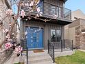 Close-up of home's entry with blue doors, modern railings, blooming tree, and address number at 3538 Pecos St, Denver, CO 80211