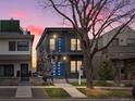 Contemporary two-story home featuring dark siding, blue doors, balconies, and mature landscaping with a tree at 3538 Pecos St, Denver, CO 80211