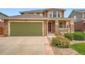 Beautiful exterior featuring a green garage door, stone accents, and a manicured lawn at 19431 E Wyoming Ave, Aurora, CO 80017
