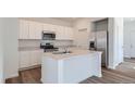 Bright kitchen featuring white cabinets, stainless steel appliances, and a center island with a sink for modern convenience at 15238 Detroit St, Thornton, CO 80602