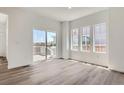 Bright living room featuring hardwood floors, a sliding glass door to a balcony, and large windows for natural light at 15238 Detroit St, Thornton, CO 80602