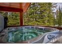 Outdoor hot tub on deck with mature forest view at 492 Kimmes Ln, Breckenridge, CO 80424