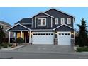 Evening view of a two-story home featuring an attached three-car garage and a welcoming front porch at 653 Glenarbor Cir, Longmont, CO 80504