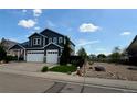 Two-story home with a well-manicured lawn, three-car garage, and tasteful landscaping against a bright blue sky at 653 Glenarbor Cir, Longmont, CO 80504