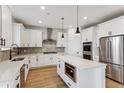 Bright, all-white kitchen features stainless appliances, herringbone backsplash, and a center island at 42984 Colonial Trl, Elizabeth, CO 80107