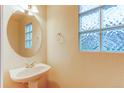 Small bathroom with pedestal sink, mirror, and glass block window at 1225 Briarhollow Way, Highlands Ranch, CO 80129