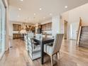 Open-concept dining area with hardwood floors flowing into a modern kitchen and staircase at 12953 Bridge View Ln, Parker, CO 80134