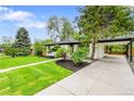 Beautifully landscaped front yard of a home with a covered carport and lush green lawn at 6526 S Elmwood St, Littleton, CO 80120