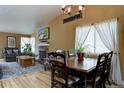 Inviting dining room with wood floors, large window, and adjacent fireplace, perfect for Gathering meals at 8745 W Ottawa Ave, Littleton, CO 80128