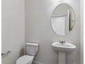 Neat half bathroom featuring a pedestal sink, oval mirror, and modern fixtures at 1923 Westport Ave, Berthoud, CO 80513