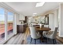 A modern dining area with wood table and chairs, a sliding glass door to the deck, and an open view of the kitchen at 43343 E Arkansas Pl, Bennett, CO 80102