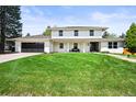 A two-story house boasts a dark garage, a lush green lawn, a front porch, and a walkway under a blue sky at 5853 S Havana Ct, Englewood, CO 80111