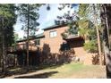 Exterior shot of back of a house with a deck and a stone foundation and accents at 9274 Sandy Ln, Conifer, CO 80433