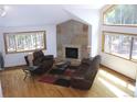 Bright living room featuring a stone fireplace, hardwood floors, and large windows with forest views at 9274 Sandy Ln, Conifer, CO 80433