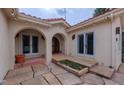 Private courtyard with stone pavers and a charming entrance featuring string lights and stucco arches at 7022 Secrest Ct, Arvada, CO 80007