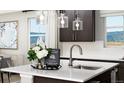 Bright kitchen island with white countertop, stainless steel faucet, and stylish pendant lighting at 9192 Telluride Ct, Commerce City, CO 80022