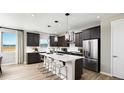 Modern kitchen features a large island with pendant lighting, stainless steel appliances, and dark cabinets at 9192 Telluride Ct, Commerce City, CO 80022
