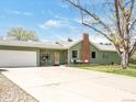A well-maintained single-story house with a light green exterior, a spacious driveway and attached garage at 2035 Carr St, Lakewood, CO 80214