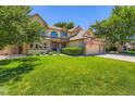 Charming two-story home with lush green lawn, mature trees, and an attached three-car garage at 11412 W Roxbury Pl, Littleton, CO 80127