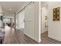 Bright hallway with wood floors and sliding barn doors leading to a bathroom and other rooms in the home at 328 Simmental Loop, Castle Rock, CO 80104