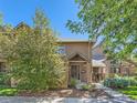 Inviting brick townhome with a covered entrance, surrounded by mature trees and well-maintained landscaping at 3540 E 5Th Ave, Denver, CO 80206