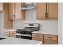 Close-up of kitchen with stainless steel range, hood and light wood cabinets at 2736 W 68Th Ave, Denver, CO 80221
