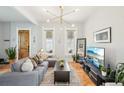 Bright living room with a gray sectional sofa, wood floors, and modern lighting fixtures at 953 Kalamath St, Denver, CO 80204