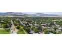 Expansive aerial view showcasing a residential area with mature trees, a park, and scenic mountain views at 12277 W Chenango Dr, Morrison, CO 80465