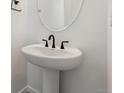 A compact pedestal sink with a dark faucet and an oval mirror at 9253 Truckee Ct, Commerce City, CO 80022