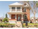 Stately two-story brick home featuring a covered porch and blooming flowerbeds at 3905 Tejon St, Denver, CO 80211
