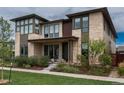 Modern two-story home featuring a stone facade, large windows, well-manicured lawn, and professional landscaping at 5866 Boston Ct, Denver, CO 80238