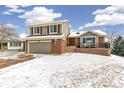 Charming two-story home with brick and gray siding, attached garage, and snowy front yard at 14126 W Harvard Pl, Lakewood, CO 80228