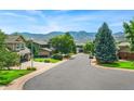 Neighborhood street view with lush green trees and beautiful mountain backdrop on clear day at 14126 W Harvard Pl, Lakewood, CO 80228