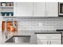 Close-up of kitchen featuring stainless steel sink, white cabinets, grey counter tops and subway tile backsplash at 20 Wilcox St # 403, Castle Rock, CO 80104