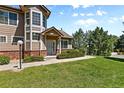 Inviting townhome with lush green lawn, mature shrubs, and walkway to entrance at 6825 S Webster St # A, Littleton, CO 80128