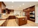 Gourmet kitchen featuring custom cabinetry, granite countertops, stainless steel appliances, and a central island at 6544 E Alaska Dr, Denver, CO 80224