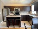 Well-equipped kitchen features stainless steel appliances, island with stool seating, and tile backsplash at 1354 Avgare Way, Erie, CO 80516
