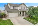 Charming two-story home with a well-maintained lawn, covered porch, attached two-car garage and concrete driveway at 11285 Iola St, Commerce City, CO 80640