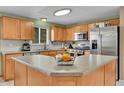 Spacious kitchen featuring an island, wooden cabinetry, stainless steel appliances and natural light at 11285 Iola St, Commerce City, CO 80640